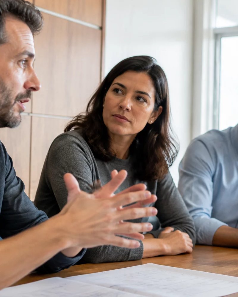 Microfone deitado sobre a mesa, com a roda de participantes fora de foco ao fundo